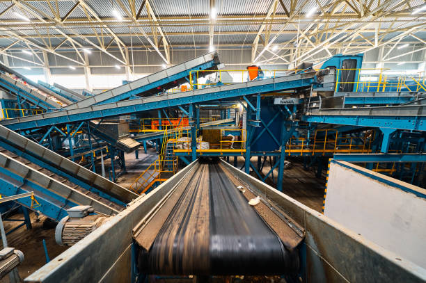 Conveyor belt carries trash pieces in recycling plant workshop closeup. Automated production line to sort rubbish. Waste materials reprocessing