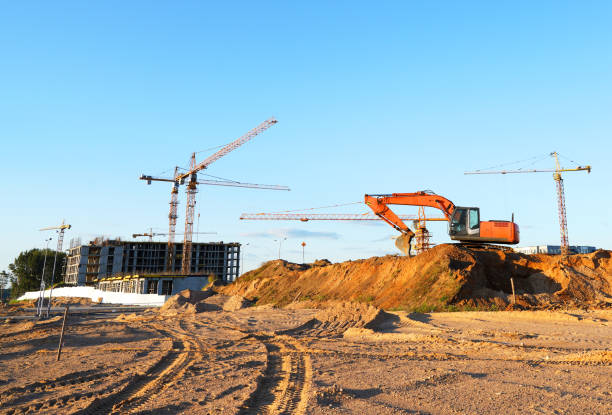 Construction site. Buildings under construction. Tower Cranes on Residential Buildings construction. Excavator on groundwork. Backhoe on roadworks. Excavator on earthworks for road construction.
