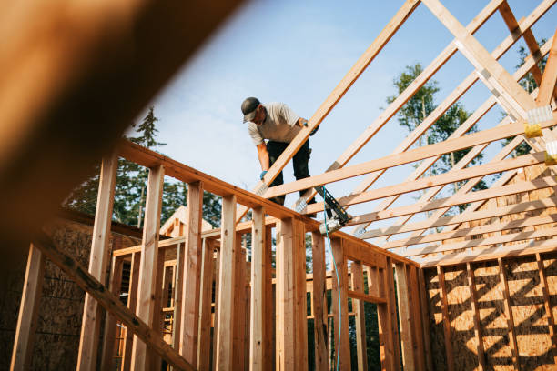 Workers build the frame of a new house project.  Bare plywood and beams as it is framed up from the foundation.  High lumber costs have affected the building process.  Shot in Washington state, USA.