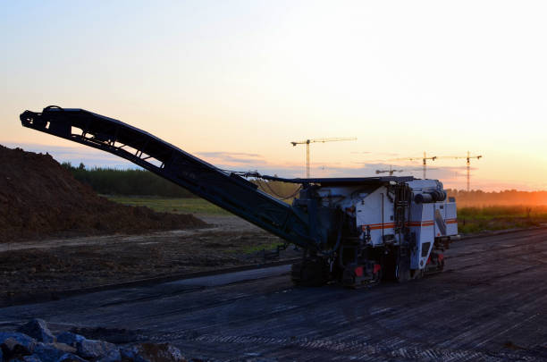 Cold milling machine on sunset background. Heavy equipment for the quick, highly efficient removal of asphalt and concrete pavements. Removing and grinding the road surface
