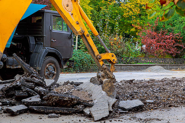 Heavy machinery breaks apart asphalt in city park area workers prepare for road repairs