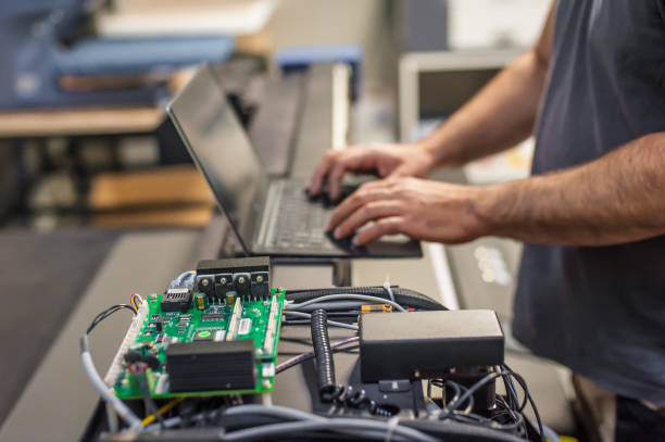 Field service maintenance engineer technician electrician inspect and control machine hardware and software system with laptop computer. Electric installation