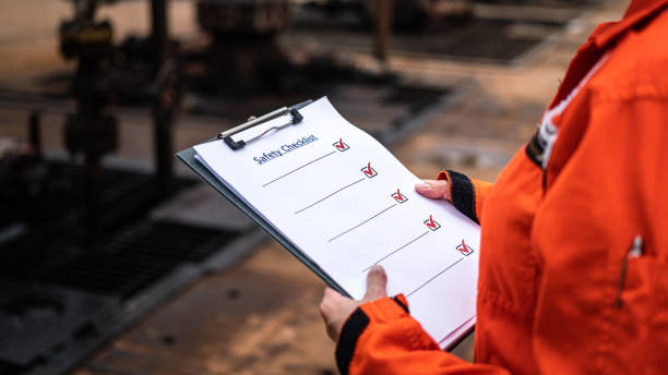 A blank safety checklist form on safety officer or operation supervisor hand, preparing to perform safety audit at construction workplace. Industrial safety working concept scene, selective focus.